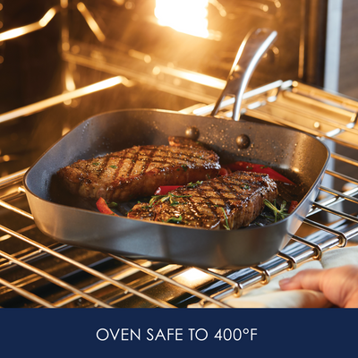 Steaks cooking in a grill pan inside an oven with a 400°F safety label.