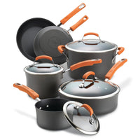A collection of nonstick pots and pans with orange handles and glass lids.