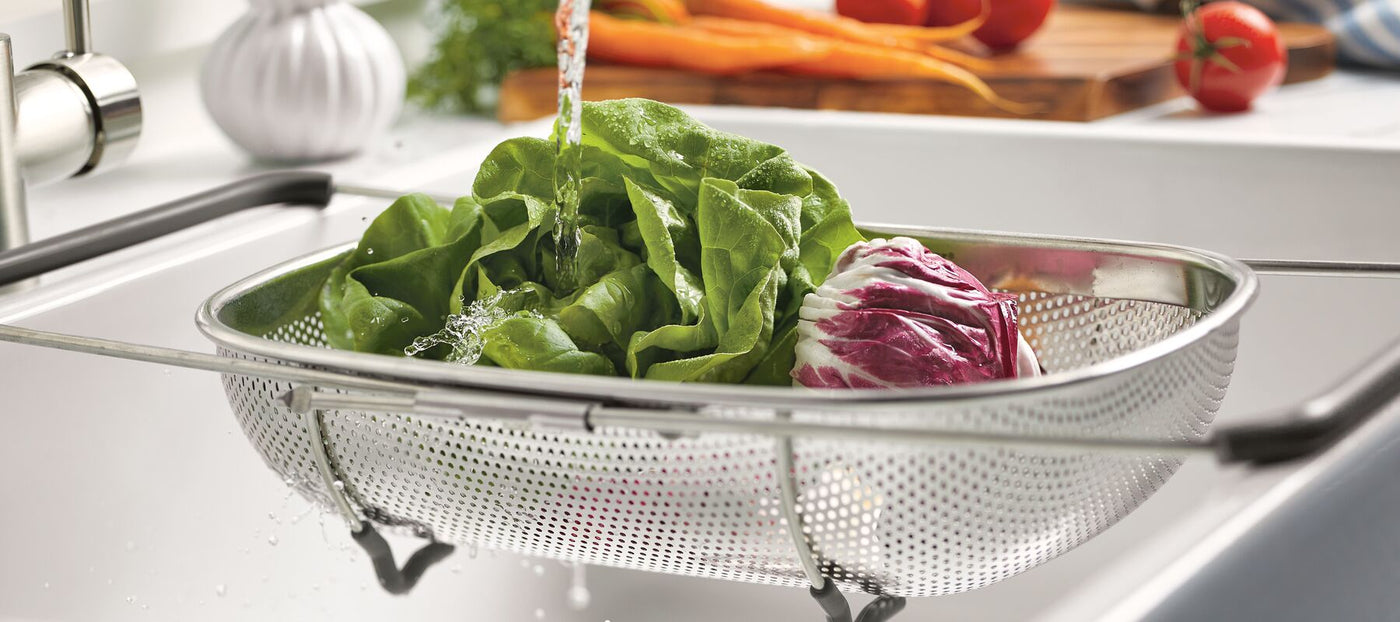 Lettuce and radicchio are gently washed in the 4.5 Quart Over-the-Sink Colander, nestled under the kitchen sink with its expandable arms ensuring a perfect fit.