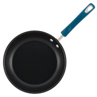 The Classic Brights Nonstick Cookware frying pan, highlighted by its vibrant blue handle, is showcased against a pristine white background. Expertly designed for ease and versatility, it’s oven-safe for all your culinary adventures.