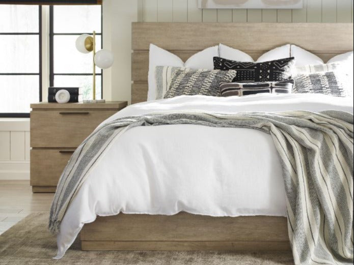 A neatly made bed with pillows and a striped blanket in a cozy bedroom.