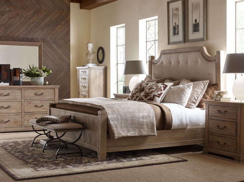 A cozy bedroom with a beige bed, wooden furniture, and decorative accents.