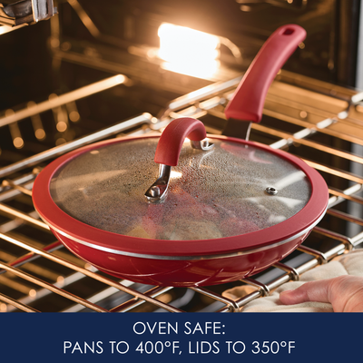 Red frying pan and lid in oven, marked as oven safe to specific temperatures.