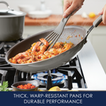 Person cooking shrimp and vegetables in a frying pan on a gas stove.