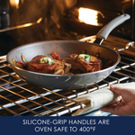 Person placing a frying pan with silicone-grip handles in an oven.