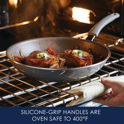 Person placing a frying pan with silicone-grip handles in an oven.