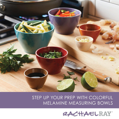 Colorful measuring bowls with fresh ingredients on a wooden kitchen counter.