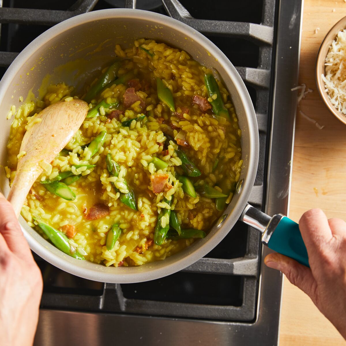 Person stirring vegetable risotto in a pot on a stove.