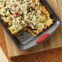 Baked vegetable lasagna in a rectangular baking dish on a woven mat.