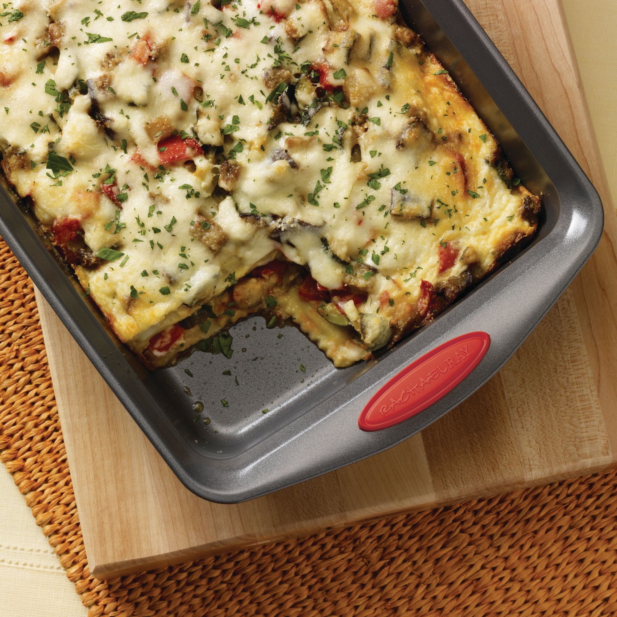 Baked vegetable lasagna in a rectangular baking dish on a woven mat.