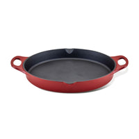 The 14-Inch NITRO Cast Iron Skillet is a vibrant red piece featuring two sturdy handles. Oven safe and induction ready, it offers style and versatility to your kitchen, set against a crisp white background.