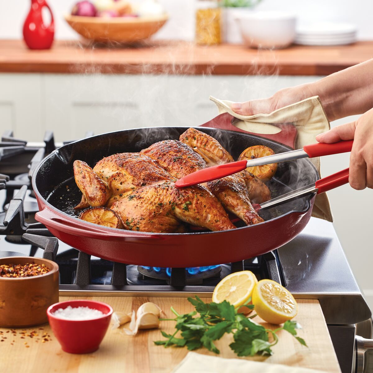A person cooks seasoned chicken with lemon slices in a 14-Inch NITRO Cast Iron Skillet, perfectly designed for an induction-ready stove.