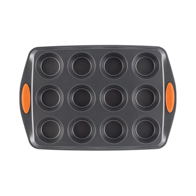 Non-stick muffin pan with twelve molds and orange silicone grips.