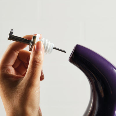 Hand adjusting a valve on a purple espresso machine.