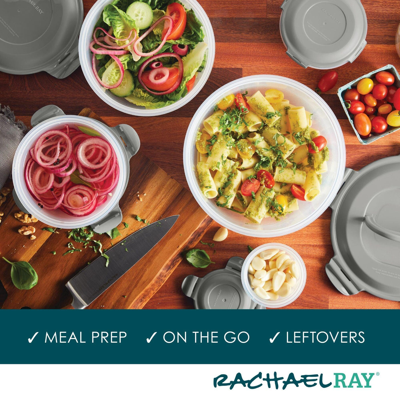 Containers with salad, pasta, and pickles on a wooden surface with lids.