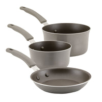 This 6-Piece Cook + Create Nonstick Cookware Set, featuring sturdy aluminum construction with various handle sizes, includes three gray pots and pans that are oven safe for versatile cooking.