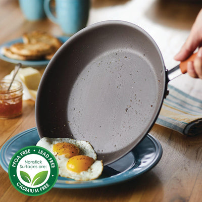 Person tilting nonstick frying pan near plate with eggs.