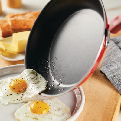 Non-stick pan with fried eggs being served onto a plate.