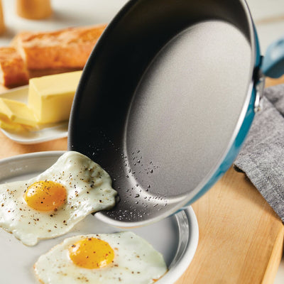 Two fried eggs on a plate next to a pan and butter slices.