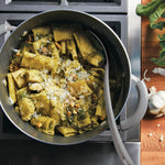 Pasta with pesto, pine nuts, and cheese in a pot on the stove.