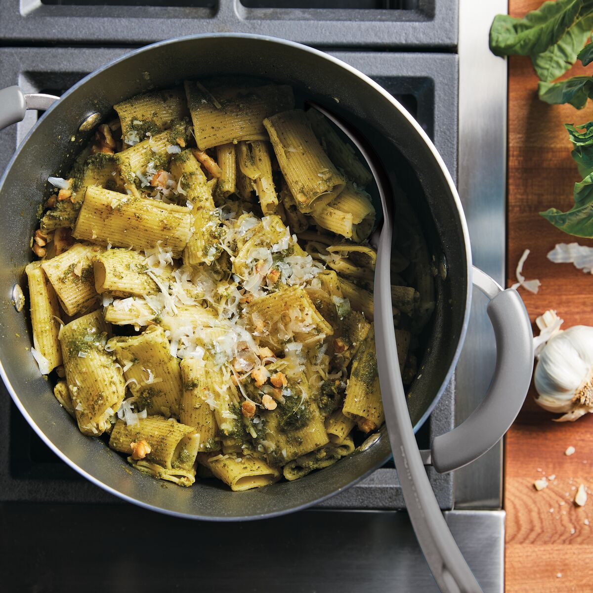 Pasta with pesto, pine nuts, and cheese in a pot on the stove.