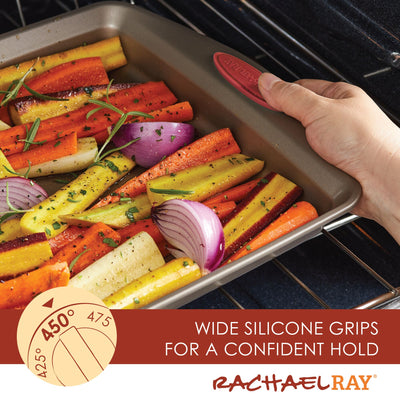 Hand placing a tray of seasoned vegetables in the oven.