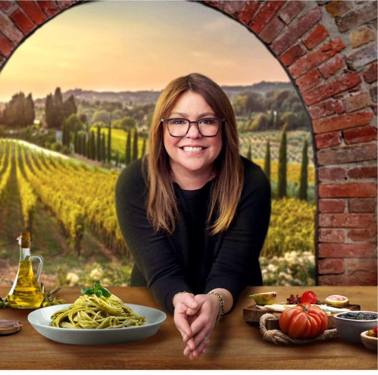 A woman smiles at a table with pasta, ingredients, and a vineyard view.