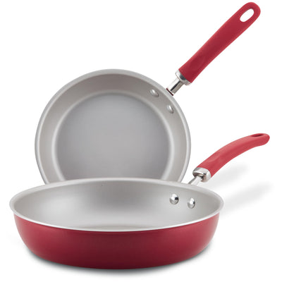 Two red frying pans with silver interiors, one stacked on the other.