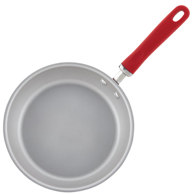 A silver frying pan with a red handle.