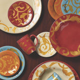 Colorful plates and mugs with ornate gold patterns on a wooden table.