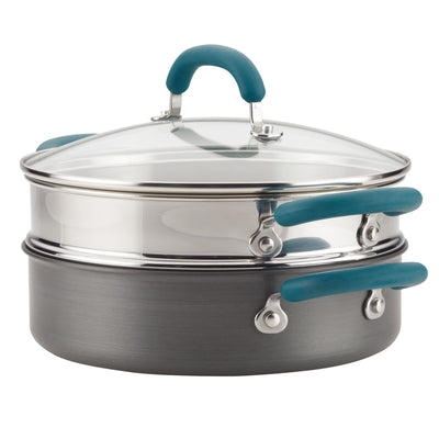 Stainless steel steamer pot with a glass lid and teal handles.