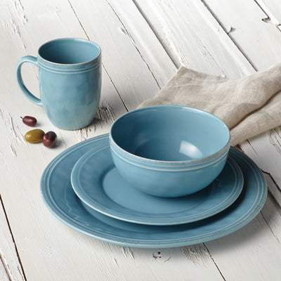 Blue dinnerware set with plates, bowl, and mug on a white wooden table.