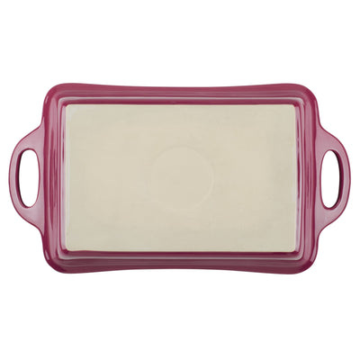 Red ceramic baking dish with handles and a cream interior.