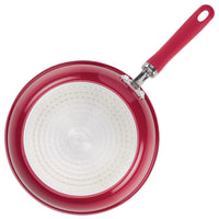 Red frying pan with a white interior and a red handle.