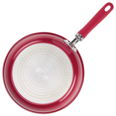 Red frying pan with a white interior and a red handle.