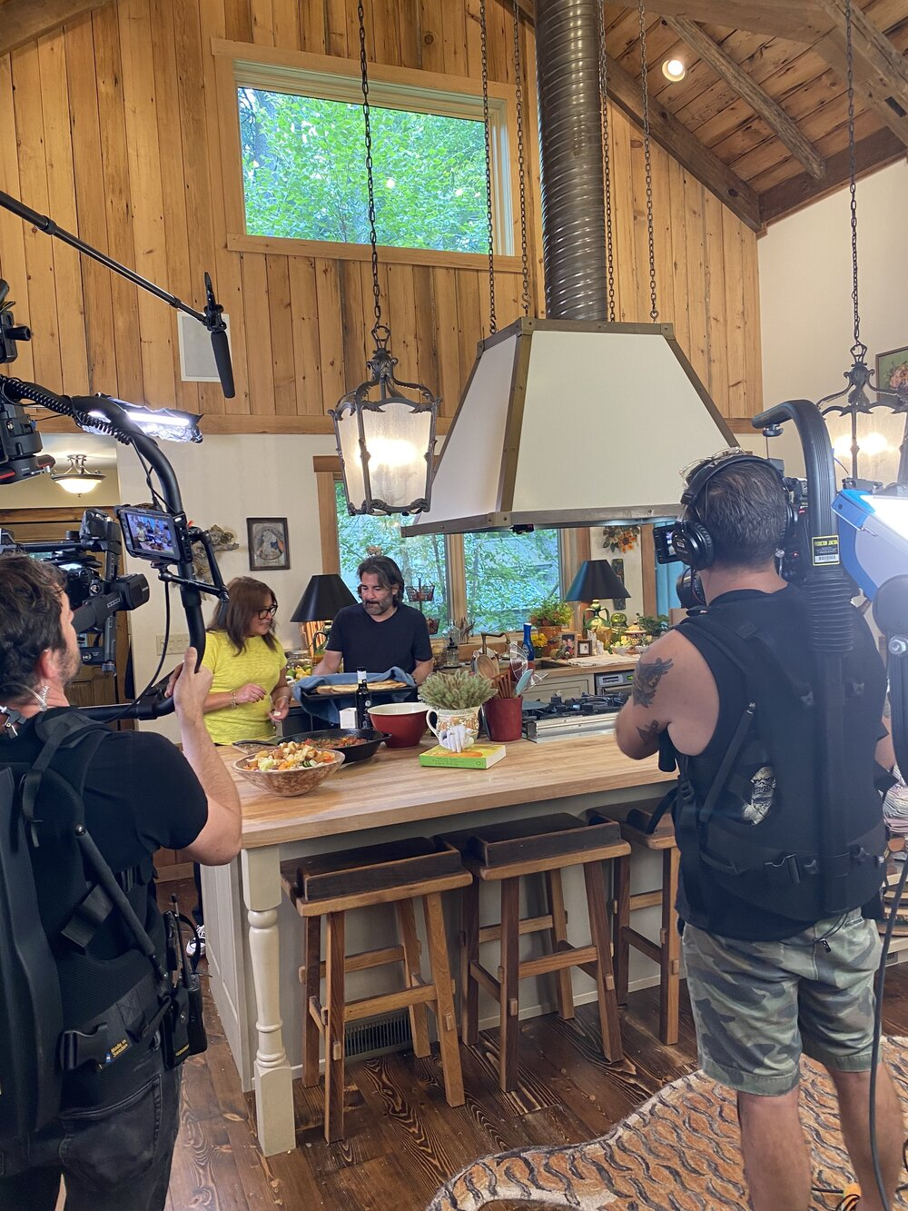 Production crew filming a cooking show in a rustic kitchen setting.