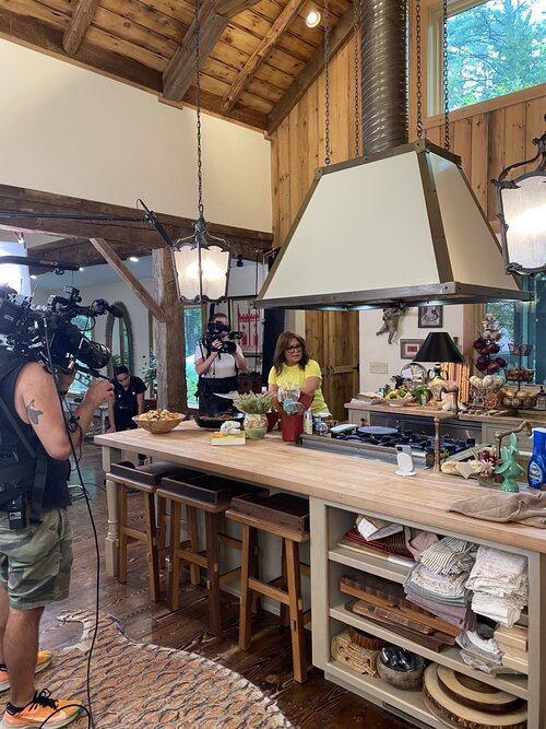 Camera crew filming a cooking show in a rustic kitchen.