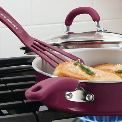 Purple pan on stove with food and a matching spatula.