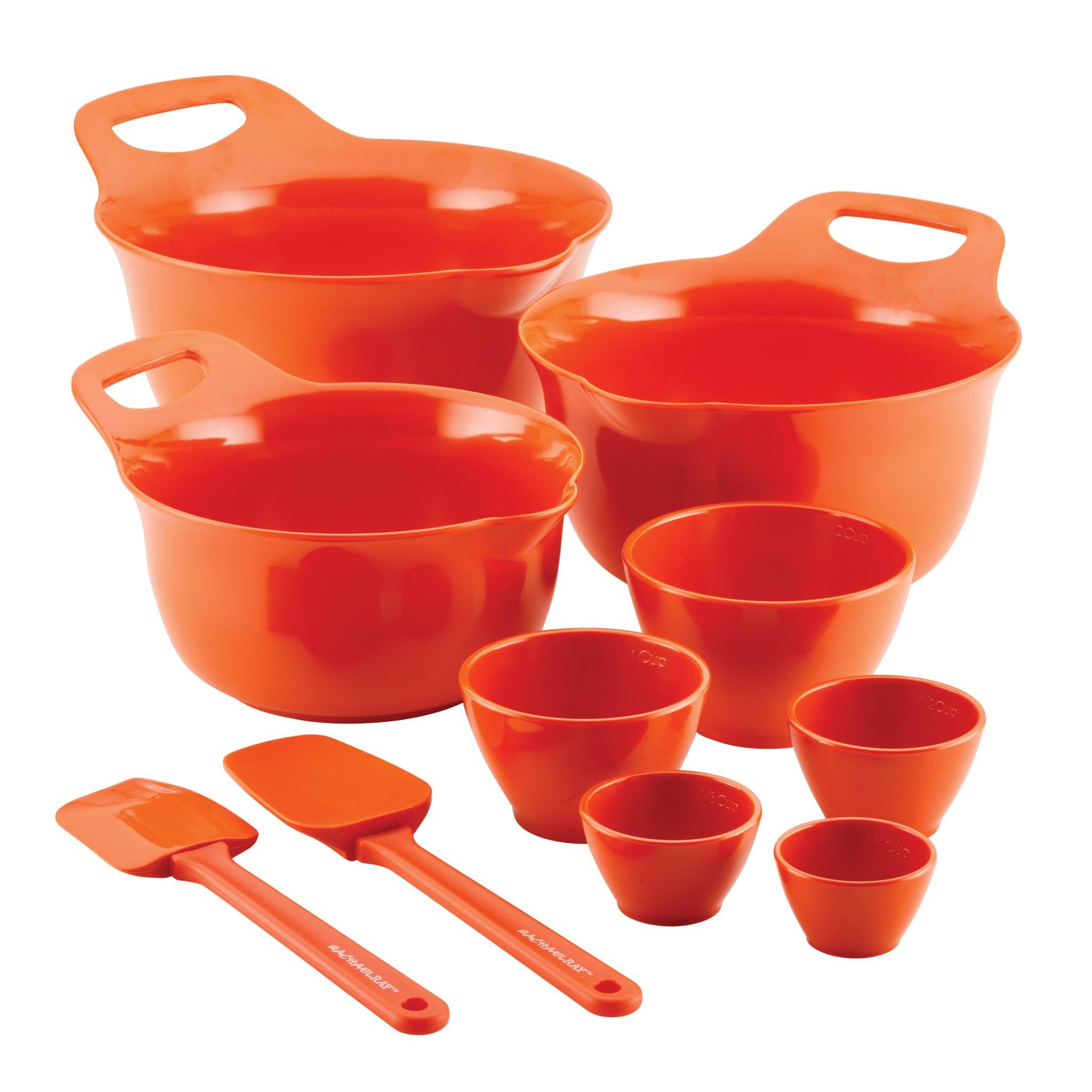 Set of orange mixing bowls and measuring cups with two spatulas.