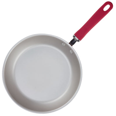 A nonstick frying pan with a red handle is shown on a white background.