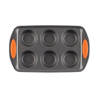 A six-cup muffin pan with orange grips on the handles.
