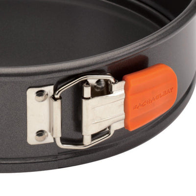 Close-up of a metal springform pan with an orange latch.