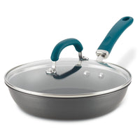 A frying pan with a glass lid and a teal handle.