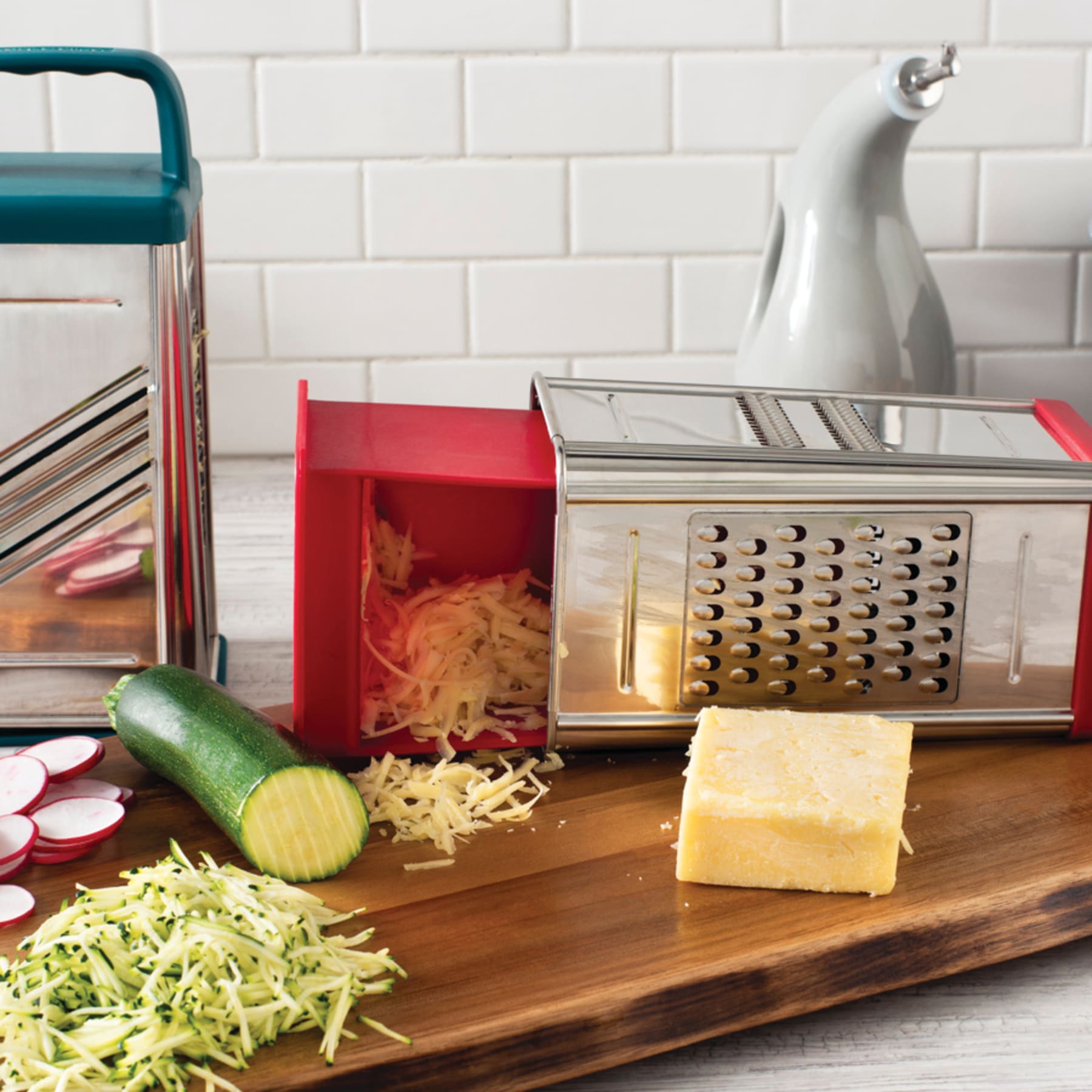 Box grater with grated cheese and zucchini on a wooden board in a kitchen.