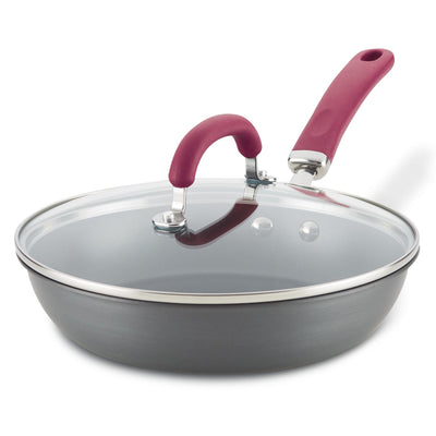 Nonstick frying pan with glass lid and red handle.