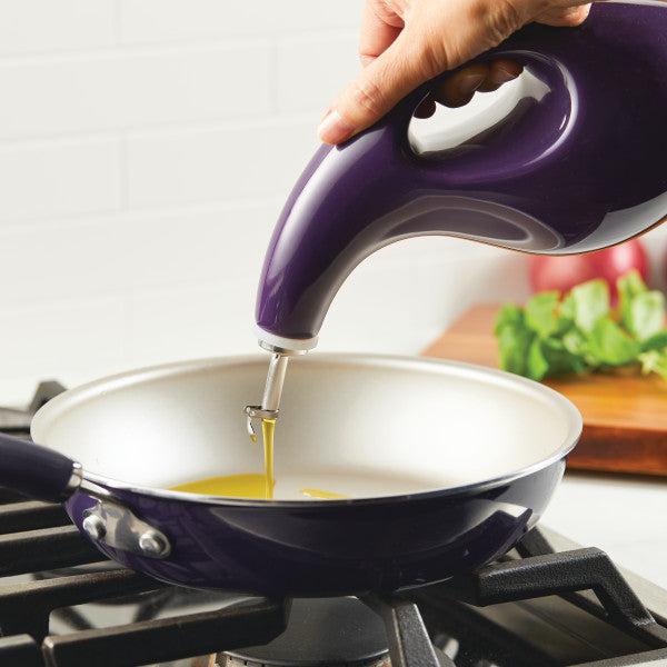 Pouring oil from a 24-ounce EVOO Bottle, equipped with a stainless steel pour spout, for precise pouring into a frying pan on the stove.