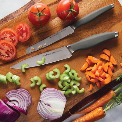 Cutting board with two knives, tomatoes, celery, onion, and carrots.