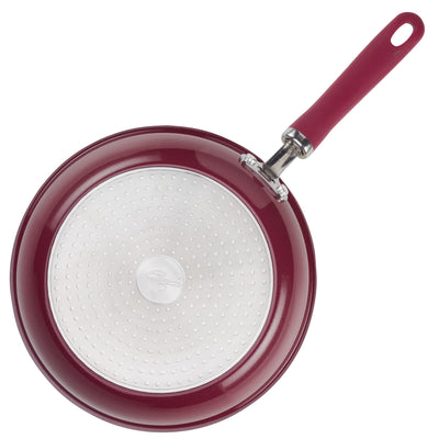 Red frying pan with a non-stick surface and a maroon handle.