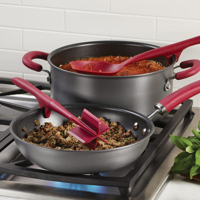 Two red-handled pots on a stove, one with sauce and the other with ground meat.