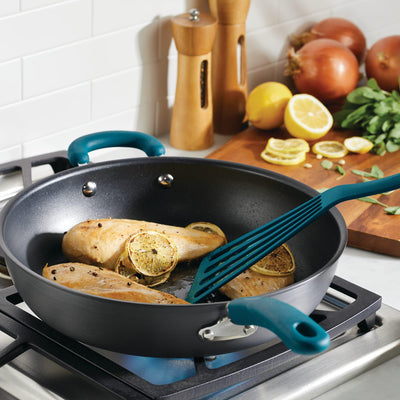 Cooking chicken with lemon slices in a pan on a stove.